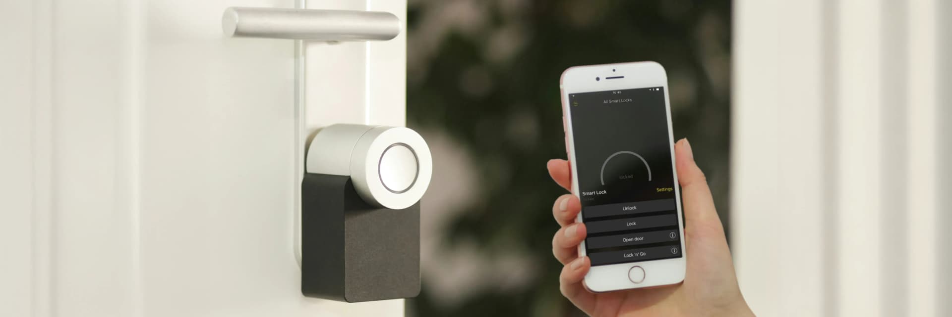 Person håller i en smartphone som styr ett digitalt hemlarm installerat på dörr – illustrerar moderna lösningar för hemlarm och säkerhetssystem.