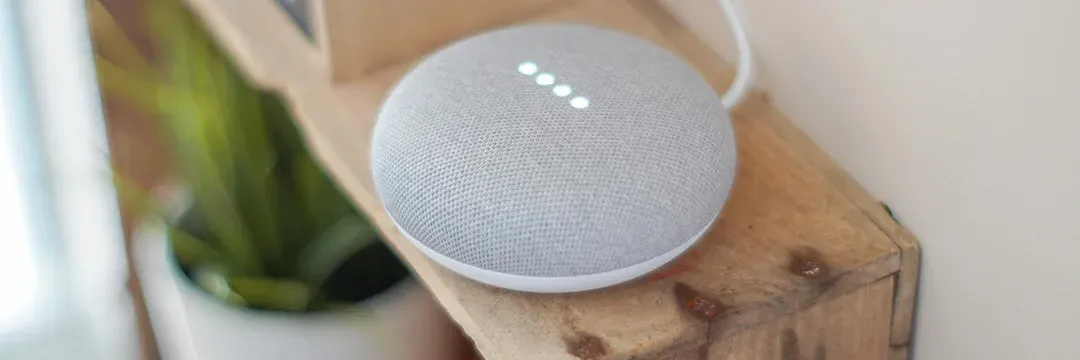 Smarthögtalare med lysande indikatorlampor placerad på en träyta – representerar moderna smarta hem-system för ökad säkerhet och bekvämlighet.