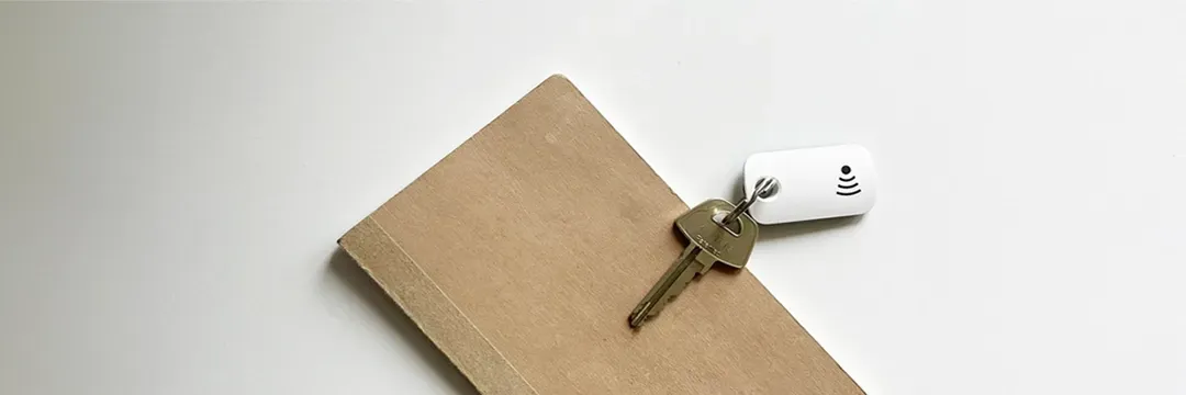 Nyckel med vit spårningsbricka på en anteckningsbok – illustrerar hur en nyckelbricka kan öka säkerheten och skydda integriteten.