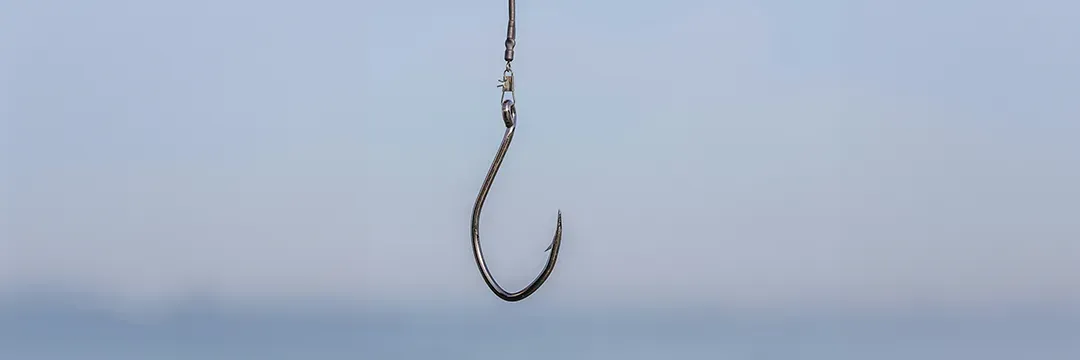 Fiskekrok som hänger i luften mot blå bakgrund – symboliserar sms-phishing och hur bedragare försöker lura till sig personlig information.