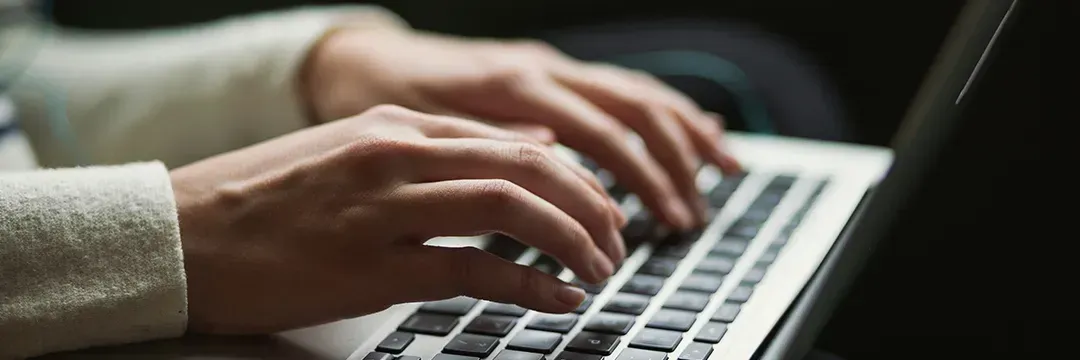 Person skriver på en bärbar dator – symboliserar hur man söker efter personer i folkbokföringsregistret online.