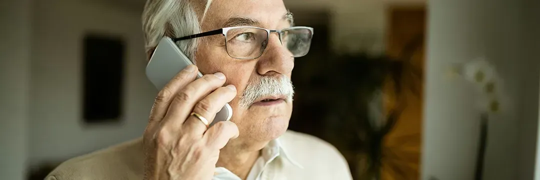 Äldre man pratar i telefon och ser bekymrad ut – illustrerar risken för telefonbedrägeri och behovet av skyddsåtgärder.